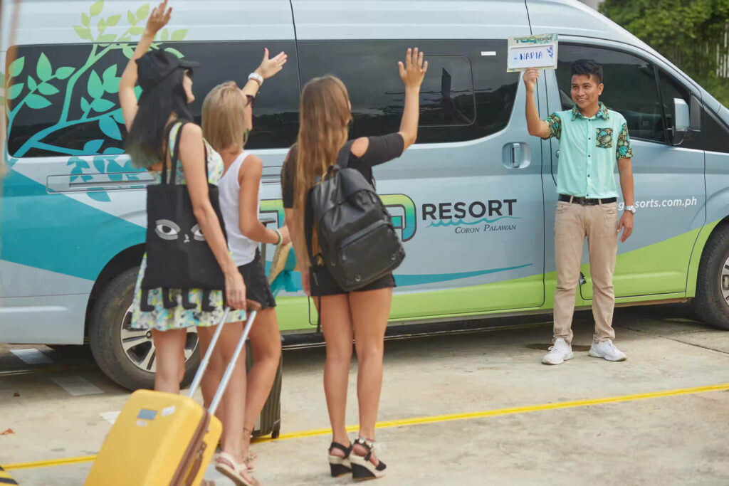 Three female friends waving at their airport transfer van driver on the way to a resort in Coron