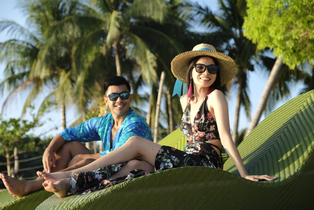 Couple relaxing on the beach during their vacation in Coron, Palawan, enjoying the clear waters and tropical scenery.
